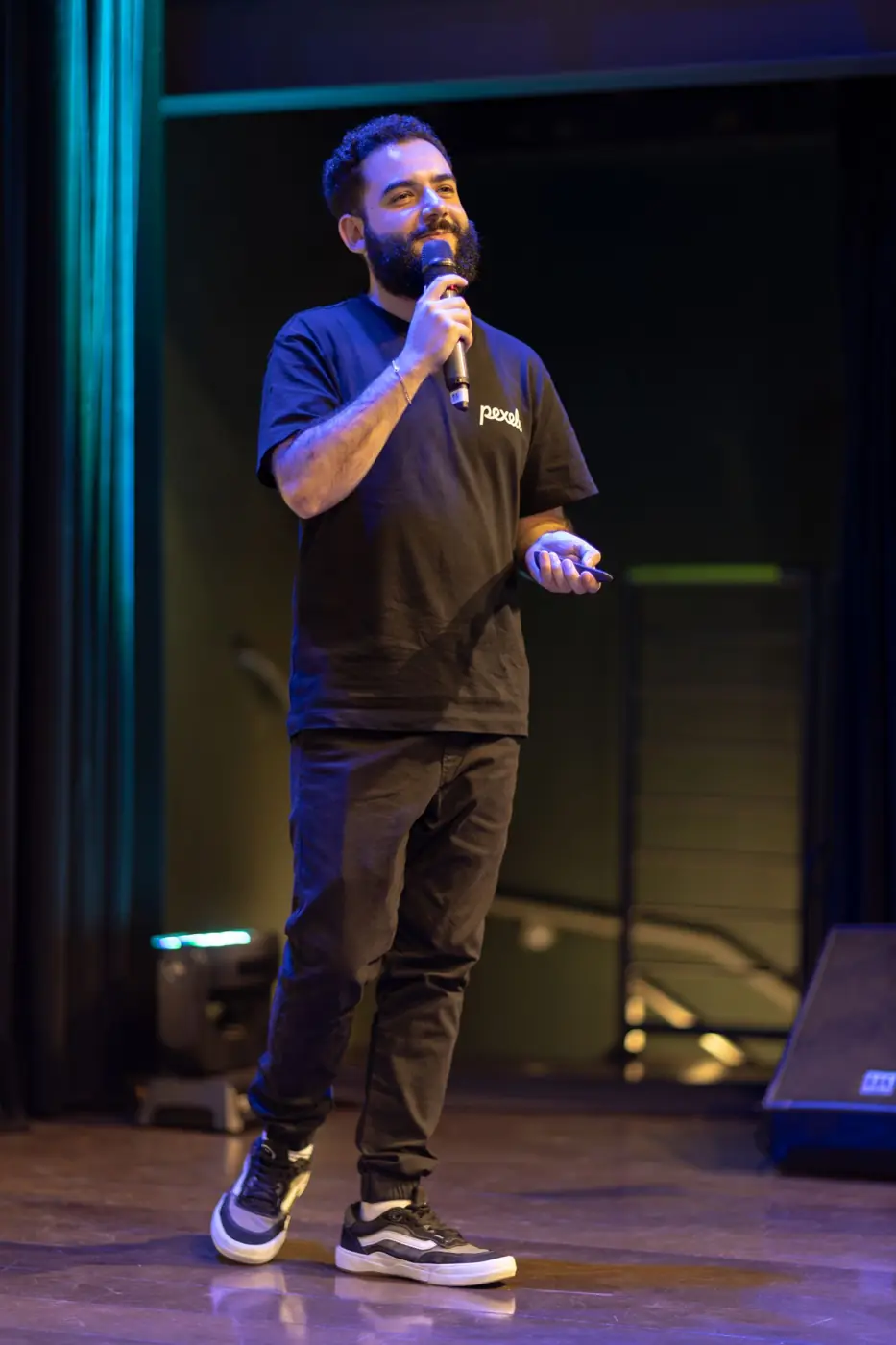 A speaker addressing the audience on a dark stage
