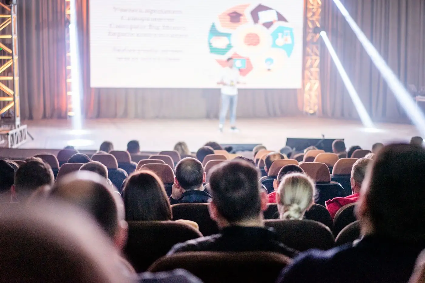 An audience watching a talk in a darkened hall